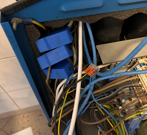 Foto av tre blå strömsensorer klämda runt ledare inuti ett blått skåp